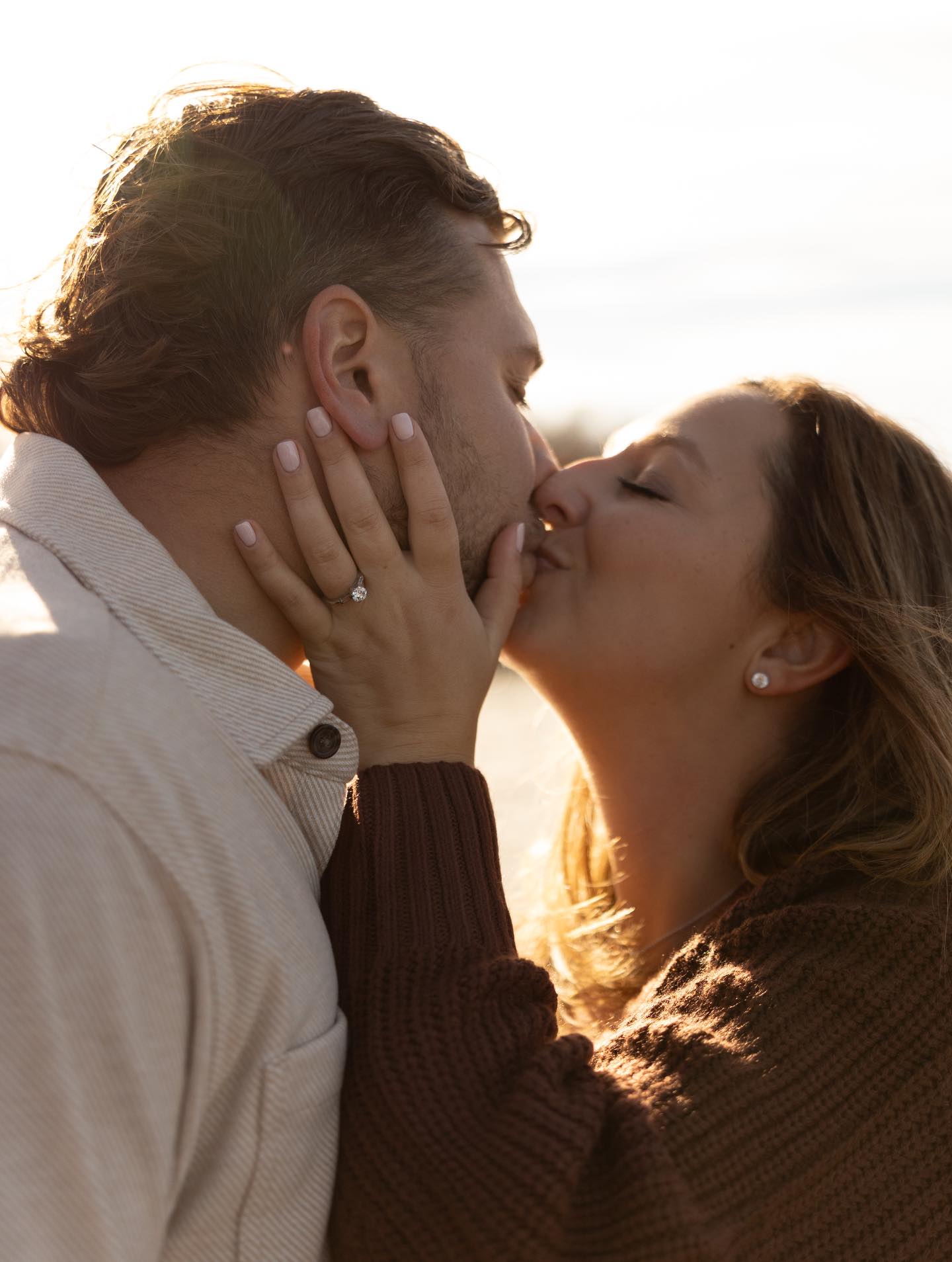 Engaged couple embracing outdoors during golden hour